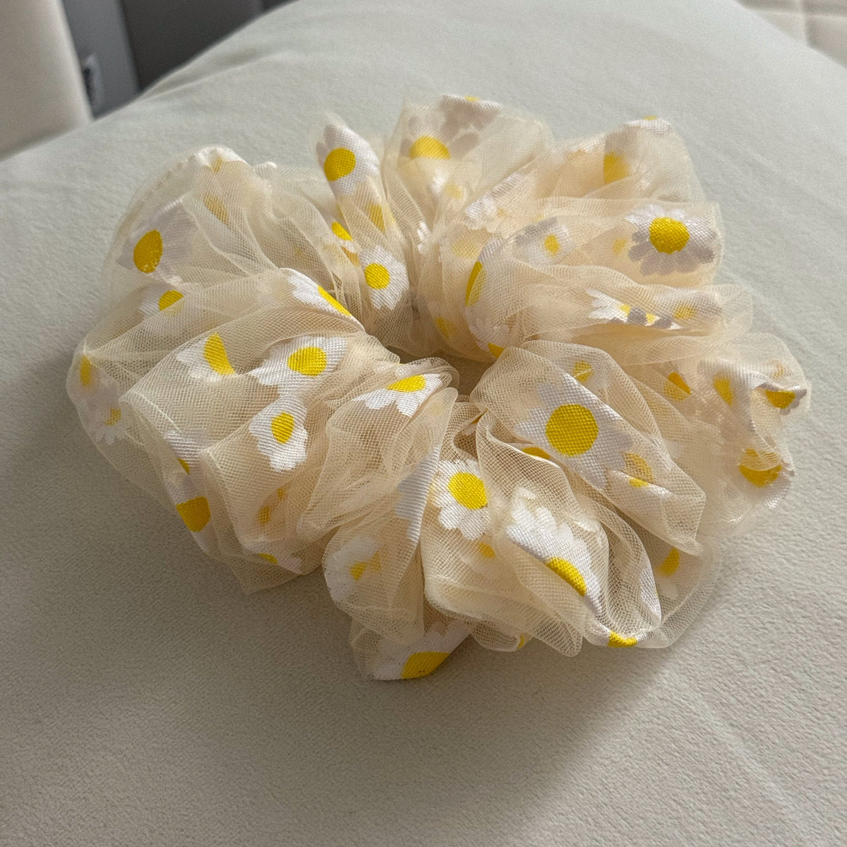 yellow scrunchie with yellow floral patterns on a light gray surface
