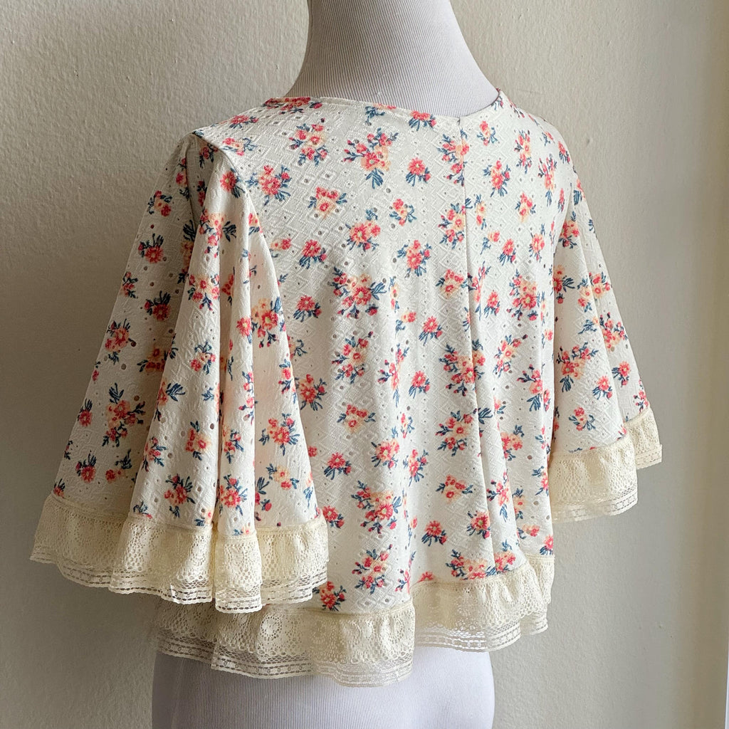 Floral blouse with lace trim on a mannequin against a plain background