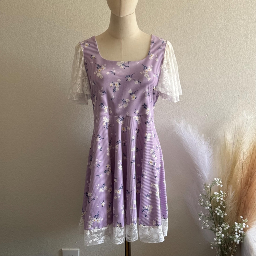 Purple floral dress on a mannequin against a plain wall with decorative elements.