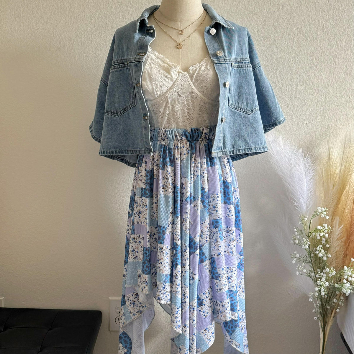 Mannequin wearing a denim jacket, lace top, and floral skirt with decorative elements.