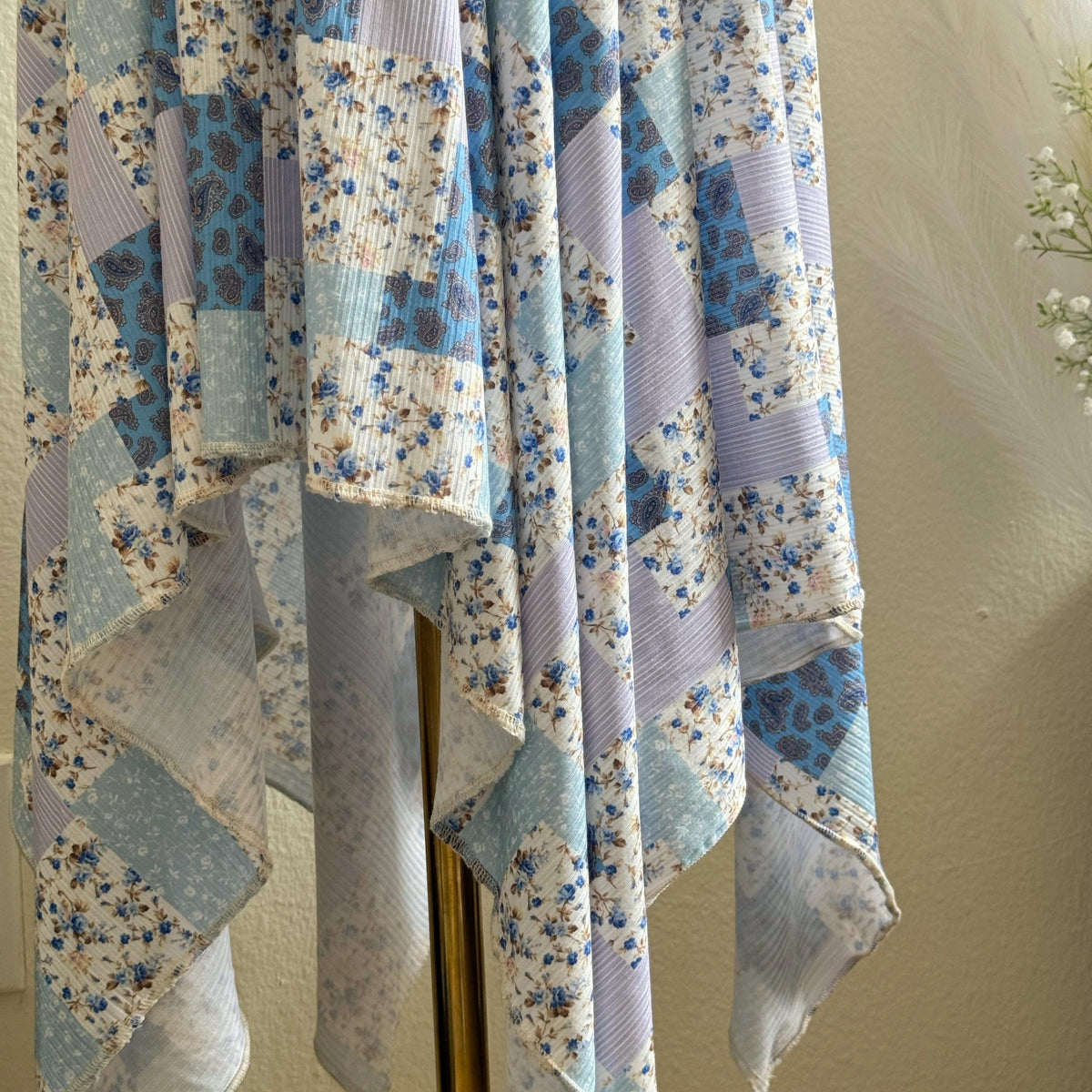 Patchwork skirt with floral patterns draped over a chair against a beige wall.