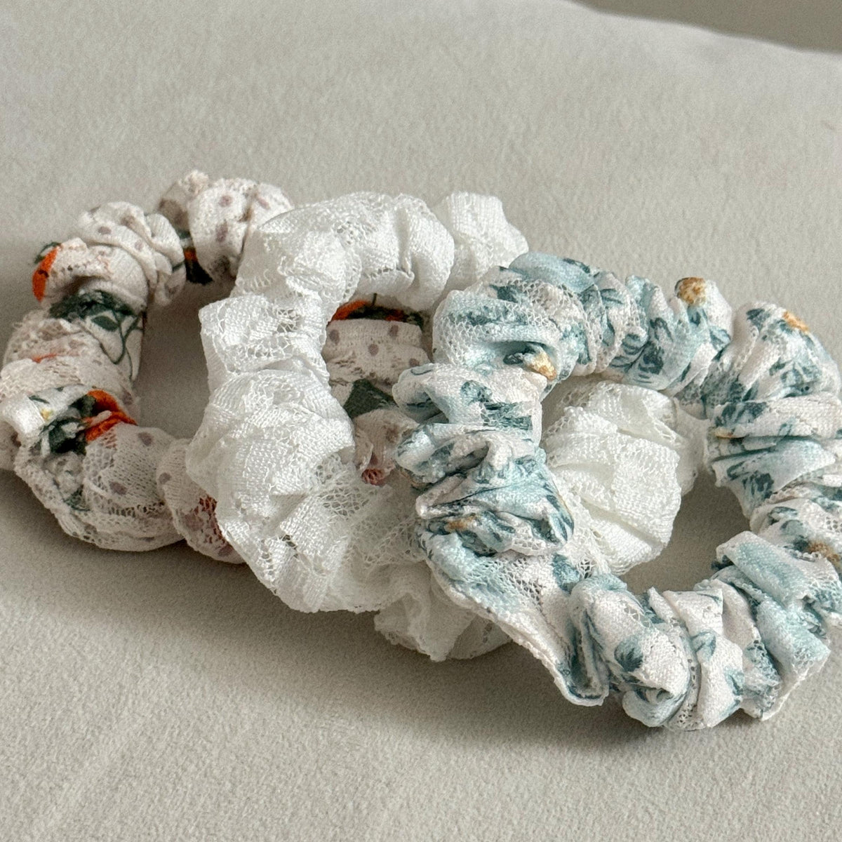 Three floral-patterned scrunchies on a light gray surface